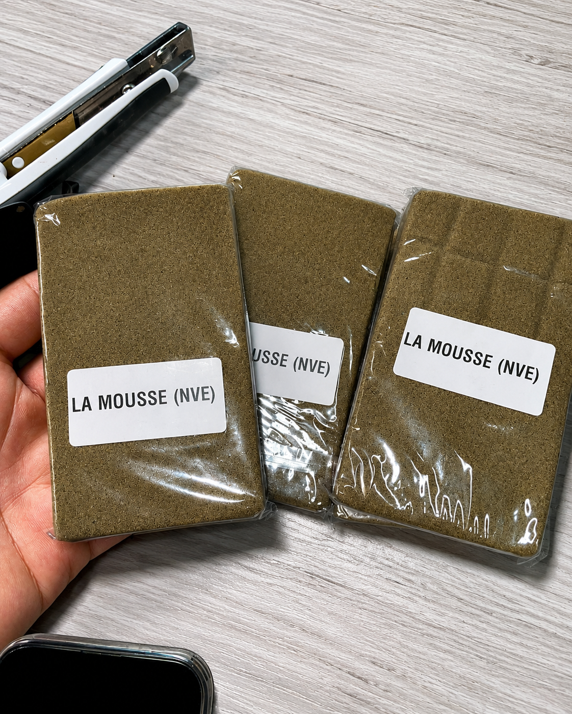 La Mousse (NVE) Hash packages in clear sealed wrapping with white product labels arranged on a light wood surface